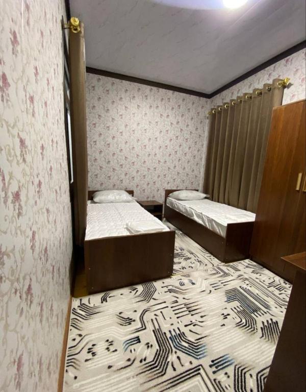 a room with two beds and a carpet at NiluNoza in Bukhara