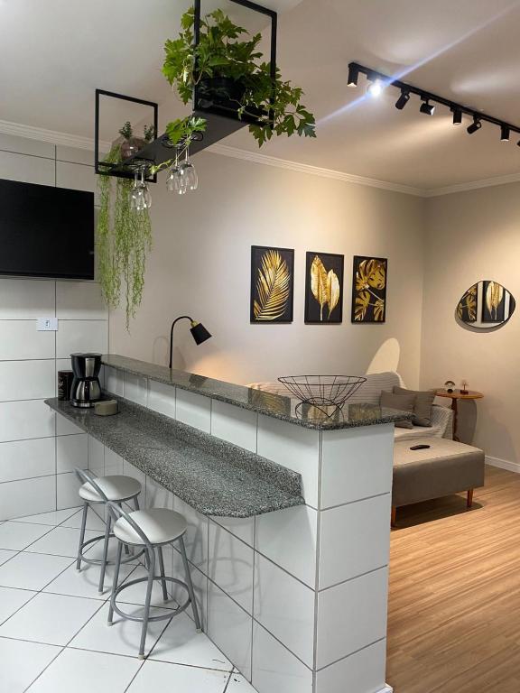 a kitchen and living room with a counter and stools at Flórida vivo bem! in São Roque