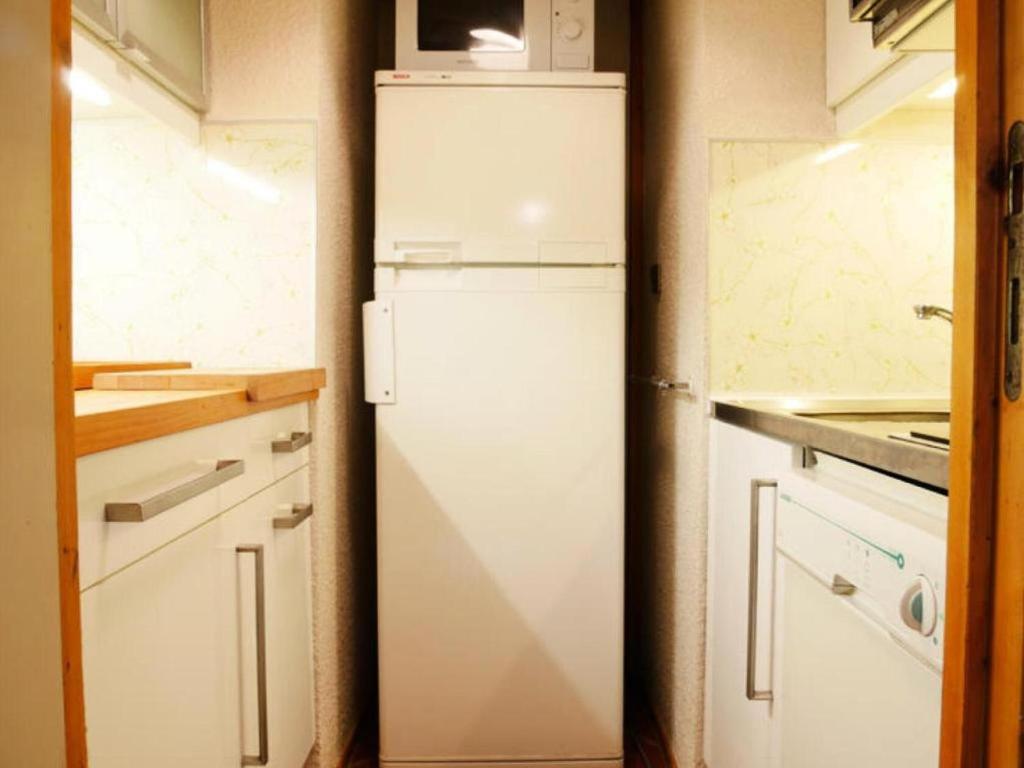 La cuisine est équipée d'un réfrigérateur blanc et d'un four micro-ondes. dans l'établissement Appartement chaleureux près des pistes avec cheminée - FR-1-181-2839, à La Plagne Tarentaise