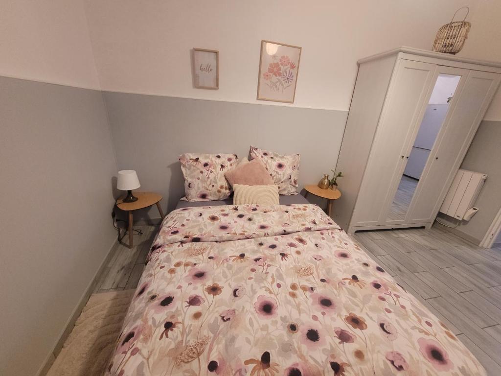 une chambre avec un grand lit avec un couvre-lit fleuri dans l'établissement Petite Maison avec son jardin et accès indépendant à 14 mn de paris, à Deuil-la-Barre