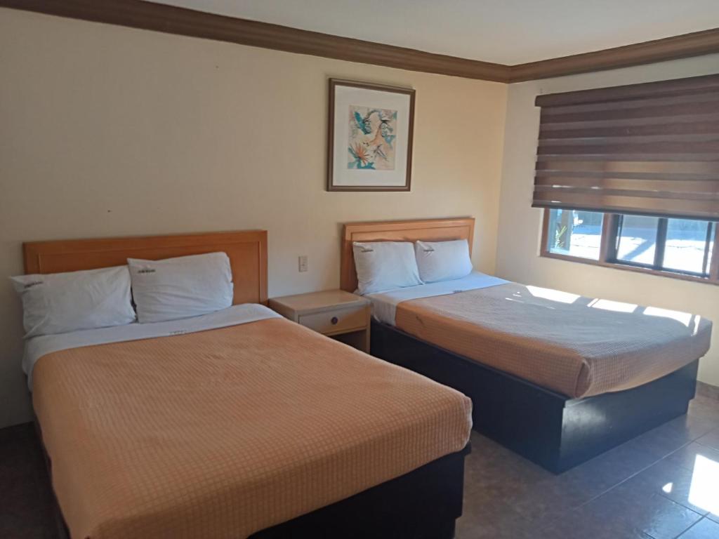 une chambre d'hôtel avec deux lits et une fenêtre dans l'établissement Hotel Coronado, à Ensenada