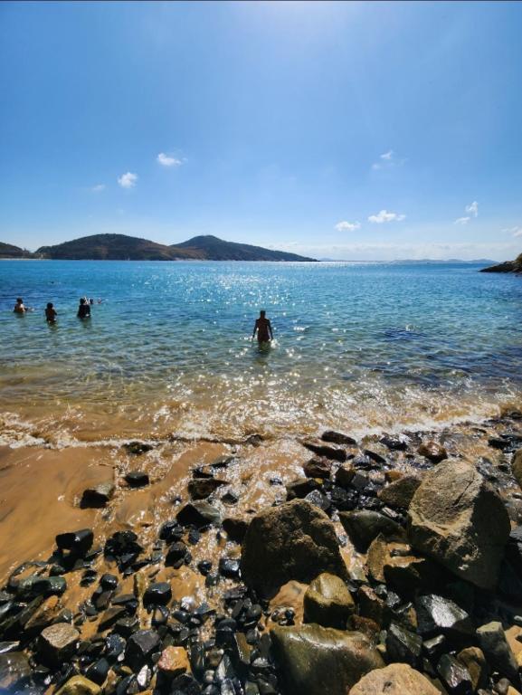 a group of people swimming in a body of water at Loft Frente ao Mar com Piscina Aquecida, Sauna Privada - Arraial do Cabo in Arraial do Cabo
