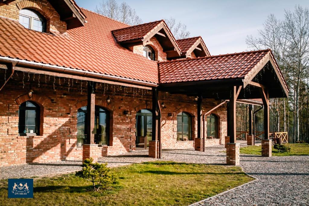 um edifício de tijolos com um telhado vermelho no topo em Dzūkijos dvaras em Alytus