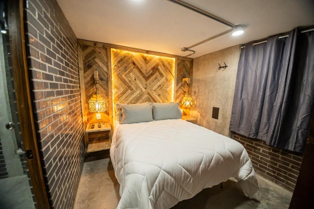 a bedroom with a white bed with a brick wall at Romance en San Miguel in San Miguel de Allende