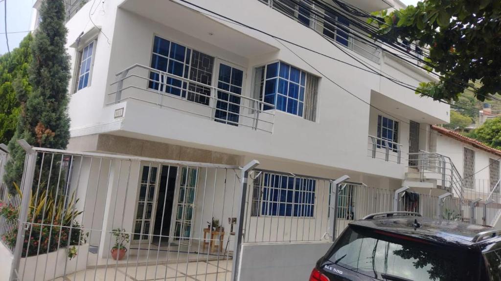 a white house with a car parked in front of it at Apartamentos Pinos del Rodadero in Santa Marta