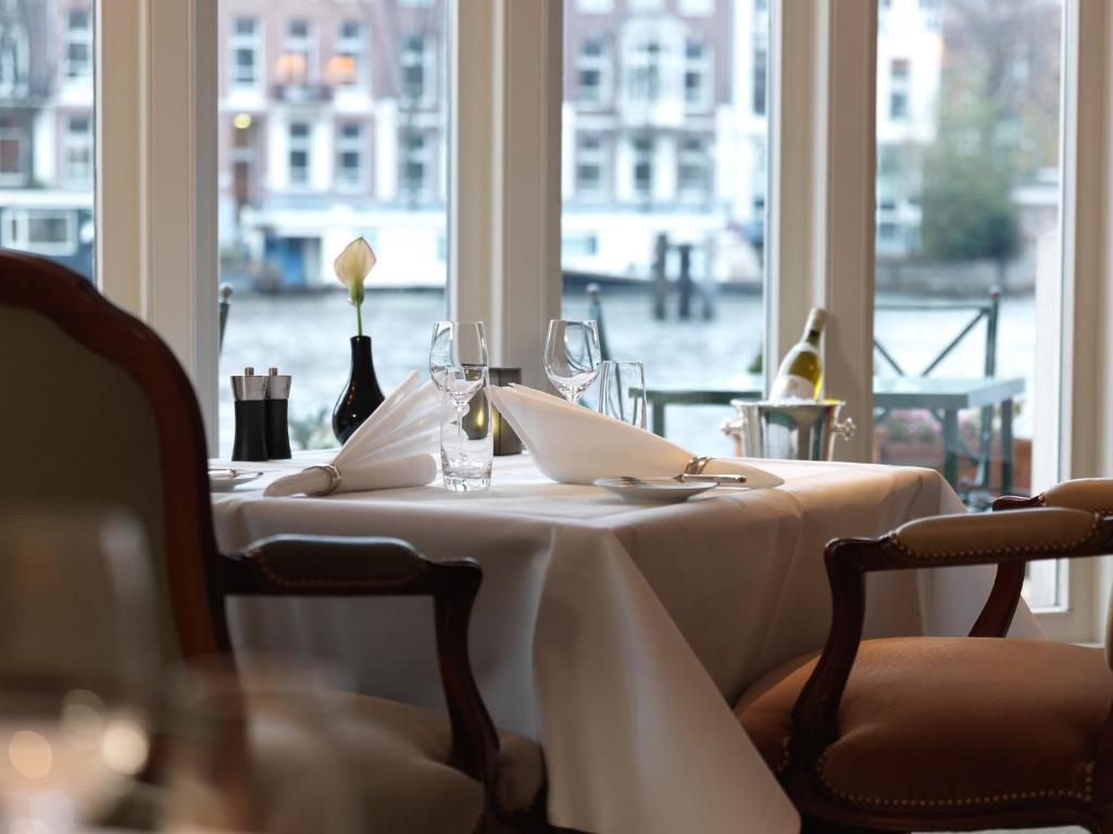 a table with a white table cloth and glasses and a window at InterContinental Amstel Amsterdam by IHG in Amsterdam