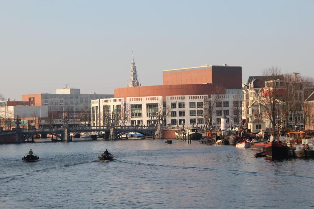 two people in boats in a river with buildings at InterContinental Amstel Amsterdam by IHG in Amsterdam