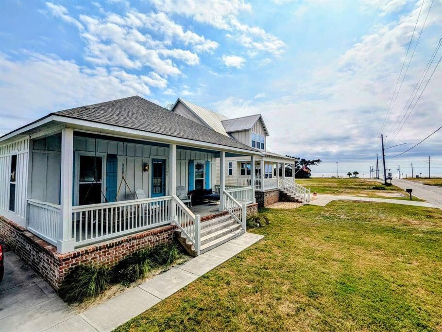 a white house with a porch and a lawn at Tegarden Cottage at Gulfport Beach in Gulfport