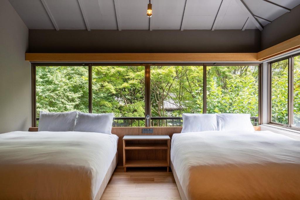 two beds in a room with a large window at n estate Kyoto-Arashiyama in Shimo saga