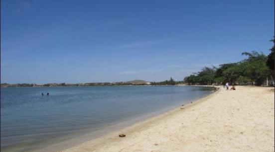 a beach with people swimming in the water at Casa perto da lagoa - Balneário São Pedro in São Pedro da Aldeia