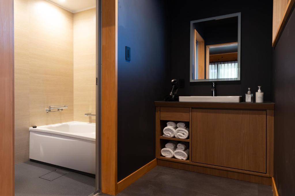 a bathroom with a tub and a sink and a bath tubermottermott at Kawaguchiko Country Cottage Ban in Fujikawaguchiko
