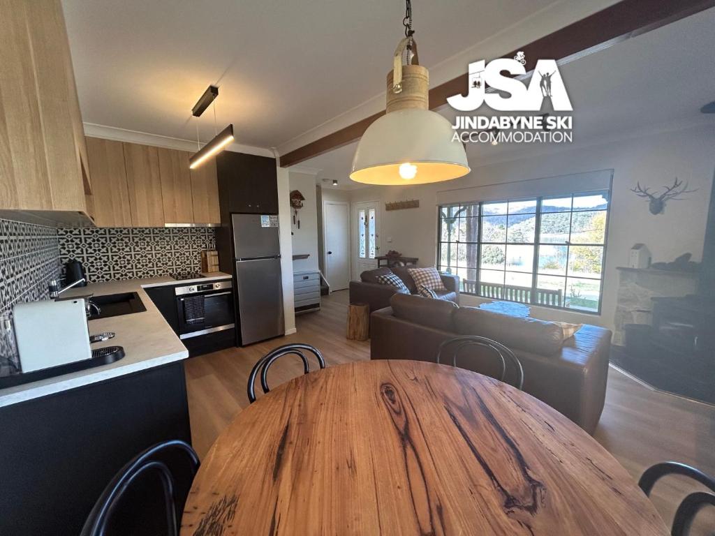 a kitchen and a living room with a wooden table at Lakeside Chalet in Jindabyne
