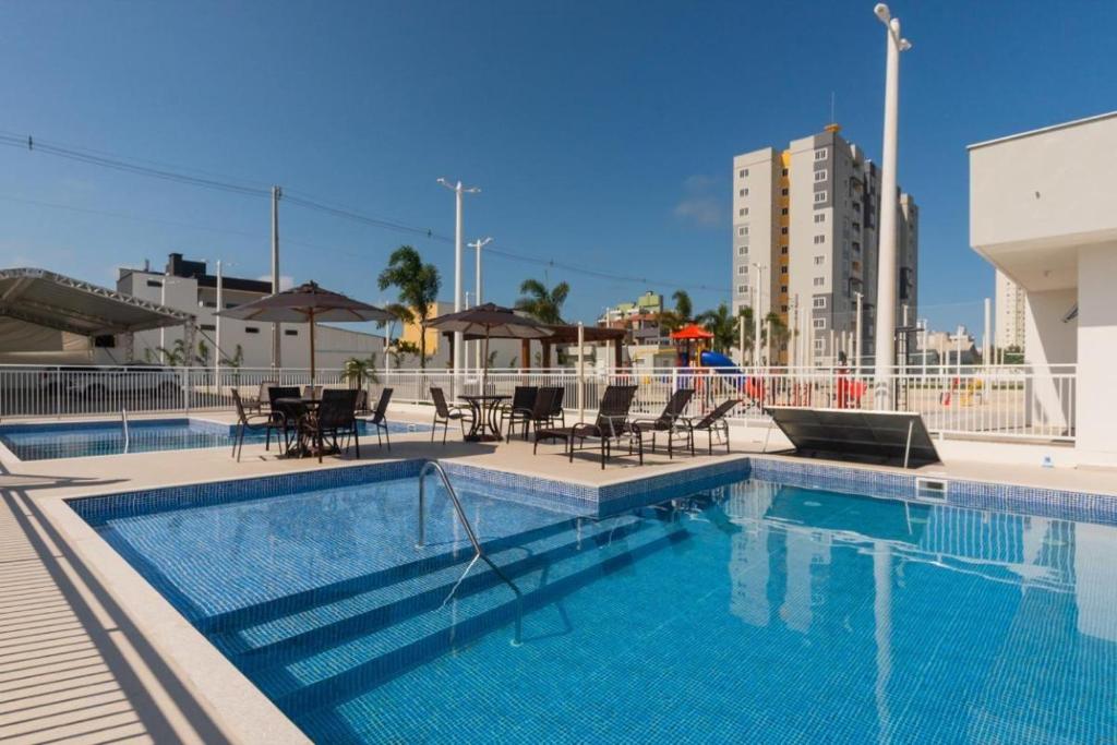 ピサーハスにあるResidencial Angelus Condomínio Clube na Praia de Piçarrasのスイミングプール(椅子、テーブル付)、