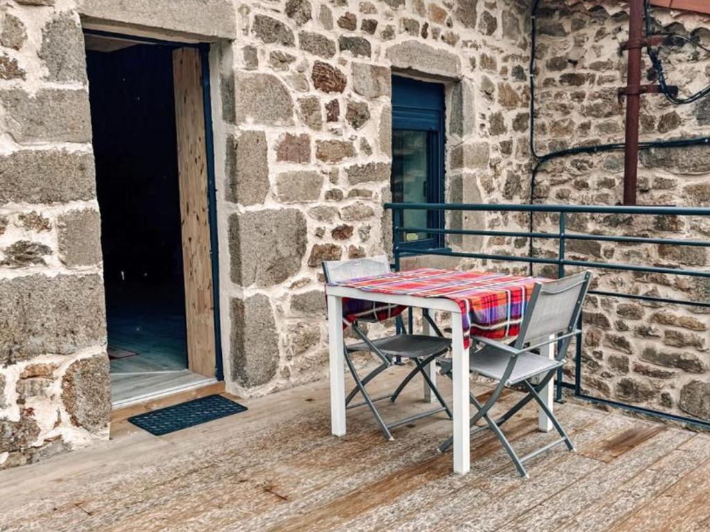 un tavolo e sedie seduti su un portico di Gîte de charme 18ème avec spa et terrasse, St-Julien-Molin-Molette - FR-1-496-335 a Saint-Julien-Molin-Molette
