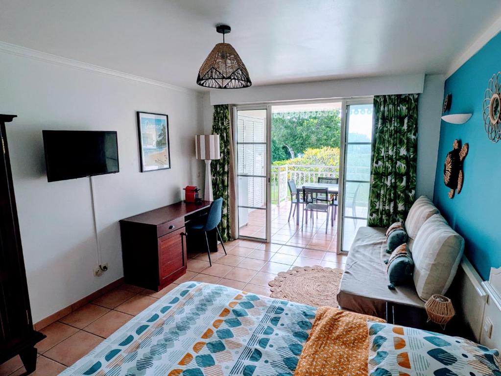 - une chambre avec un lit, un bureau et une télévision dans l'établissement Ti'Karaïb Appartement Vue Mer, à Sainte-Luce
