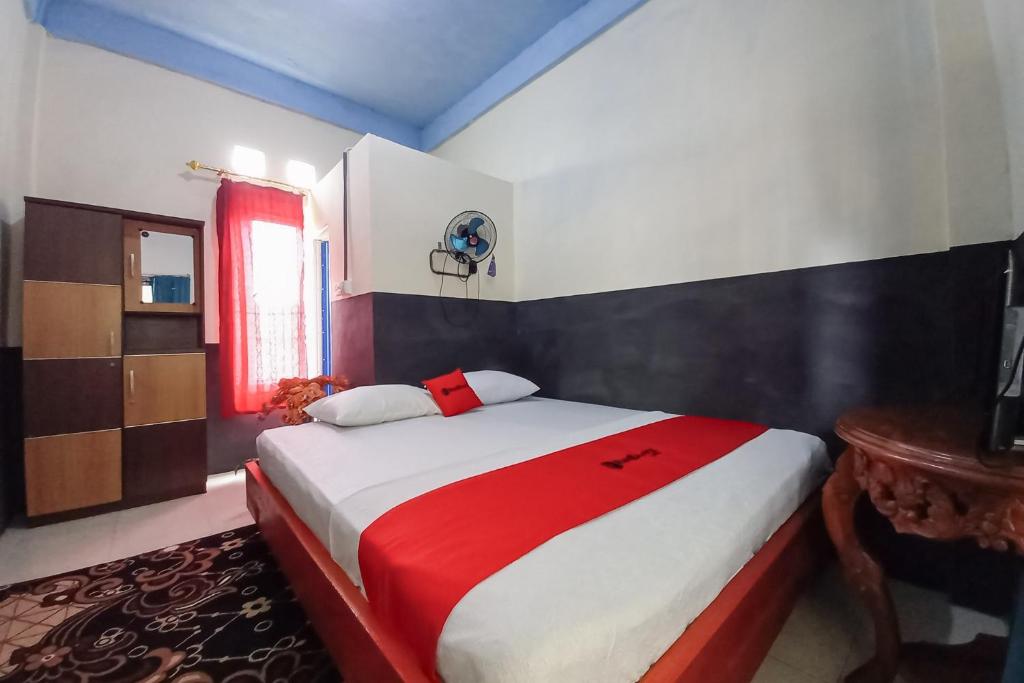 a bedroom with a large bed with a red blanket at RedDoorz Syariah at Penginapan Queen Sungai Penuh in Sungaitutung