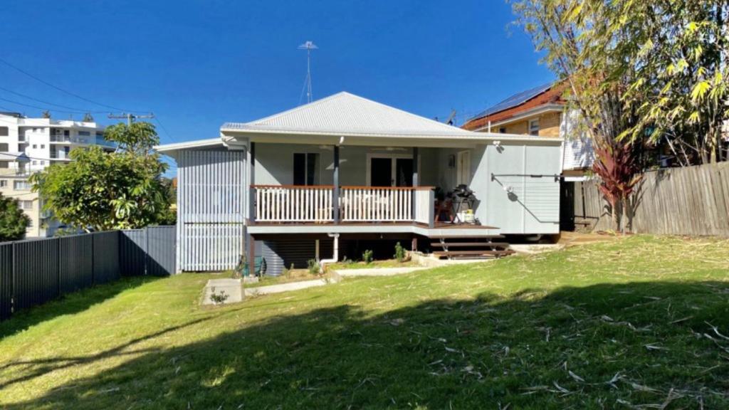 a white house with a fence and a yard at Blue Beach House in Caloundra