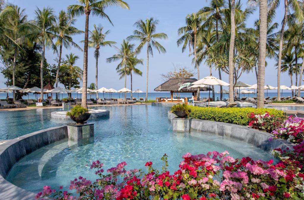 a pool at the resort with flowers and palm trees at Katathani Phuket Beach Resort - SHA Extra Plus in Kata Beach