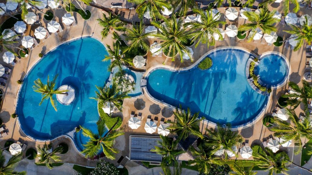an overhead view of a swimming pool with palm trees at Katathani Phuket Beach Resort - SHA Extra Plus in Kata Beach