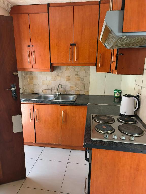 une cuisine avec des armoires en bois et un four à plaques de cuisson dans l'établissement Rozza Self-catering Accommodation, à UTW