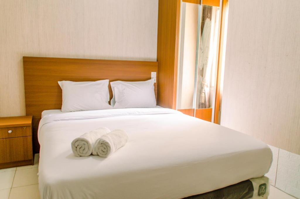 a bedroom with a bed with two towels on it at Simply and Cozy Pool View 2BR at Great Western Apartment By Travelio in Pumpangsineng