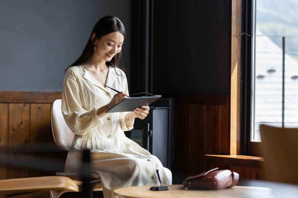a woman sitting in a chair looking at a tablet at Kawaguchiko Country Cottage Ban in Fujikawaguchiko