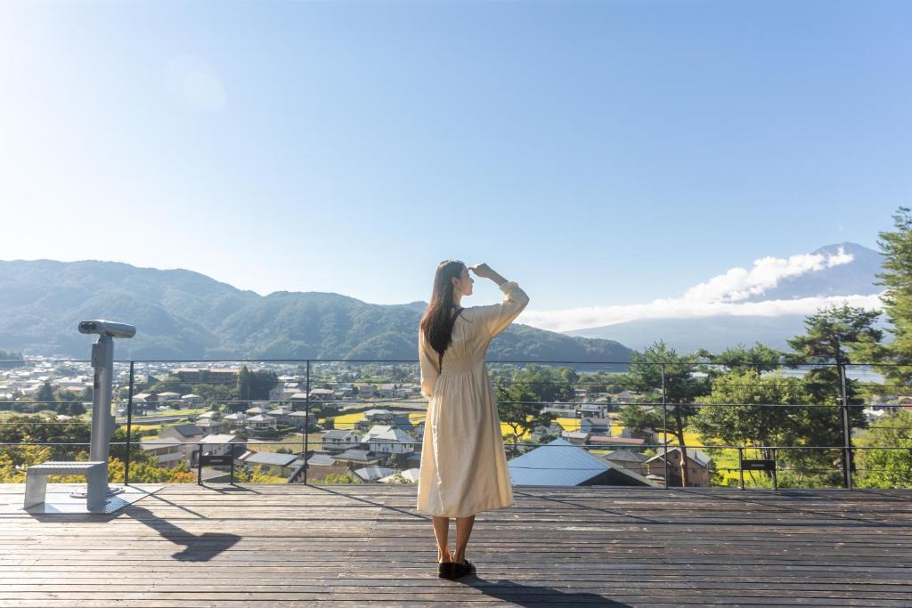 a woman standing on a deck looking at the city at Kawaguchiko Country Cottage Ban in Fujikawaguchiko