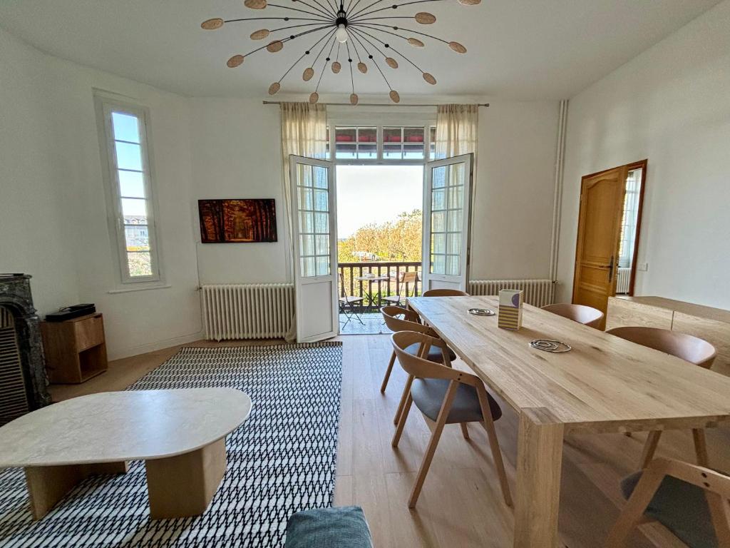 a living room with tables and chairs and a chandelier at Mermoz Vue Mer, Parking in Deauville