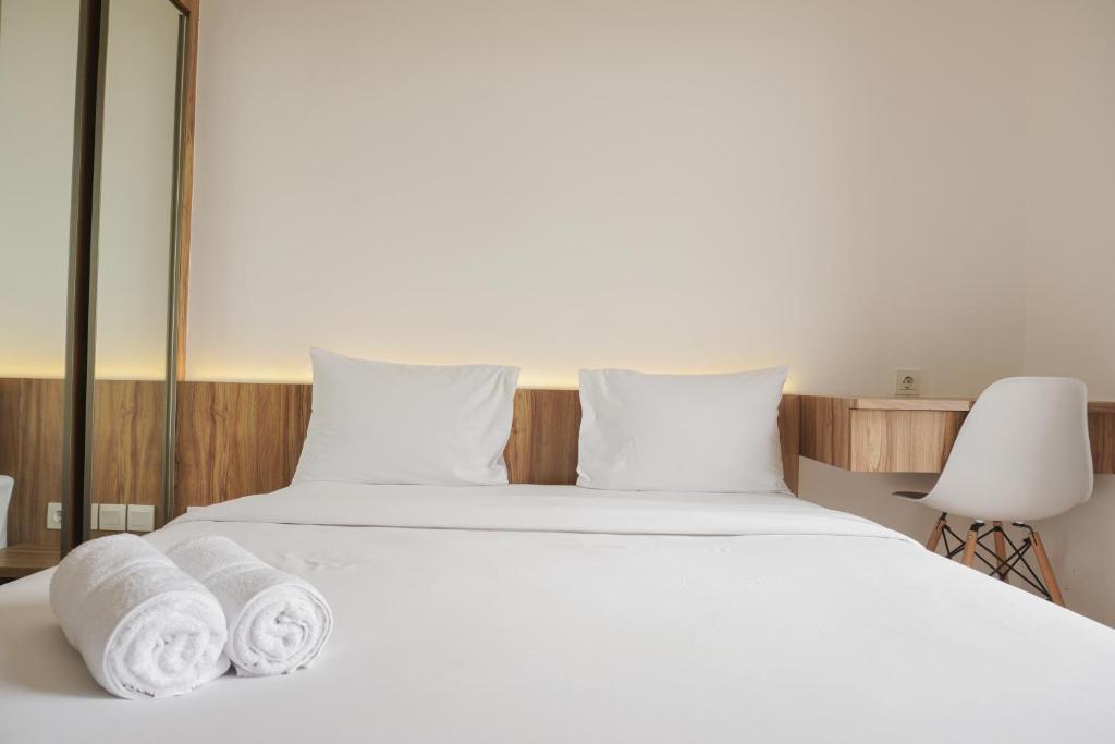 a bedroom with a white bed with towels on it at Fully Furnished with Pleasure 2BR at Sky House BSD Apartment By Travelio in Tangerang