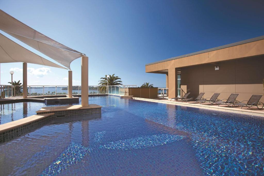 Una piscina con sillas y un edificio. en Rydges Hotel Port Macquarie, en Port Macquarie