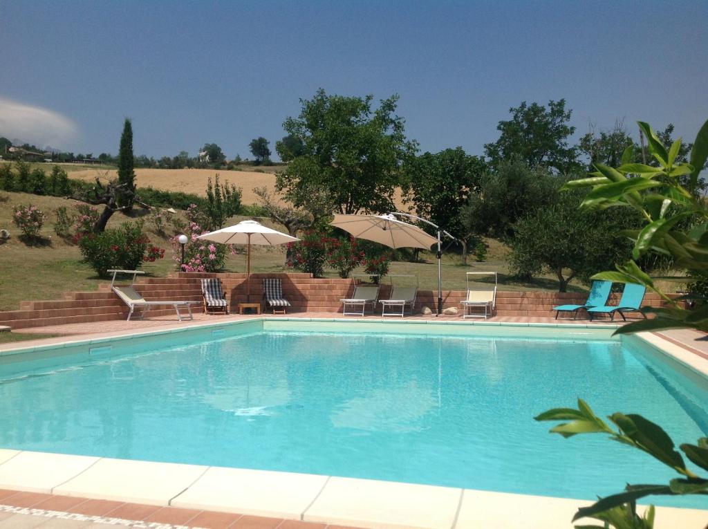 una piscina con sillas y sombrillas en Casa Carolina Santa Maria, en Montebello di Bertona