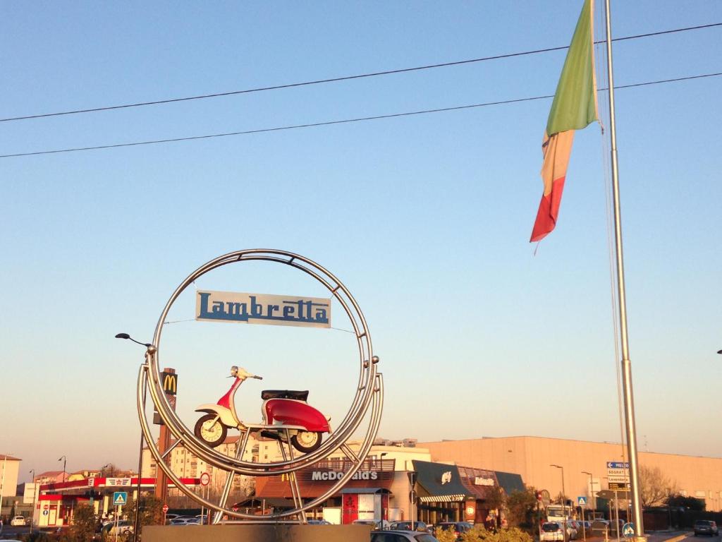 a sign with a scooter in a metal circle at Lambretta's Home in Milan