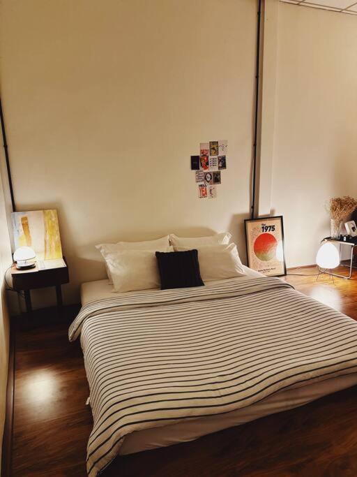 a bedroom with a large bed with striped sheets at Janatyy Guest House Suratthani in Suratthani