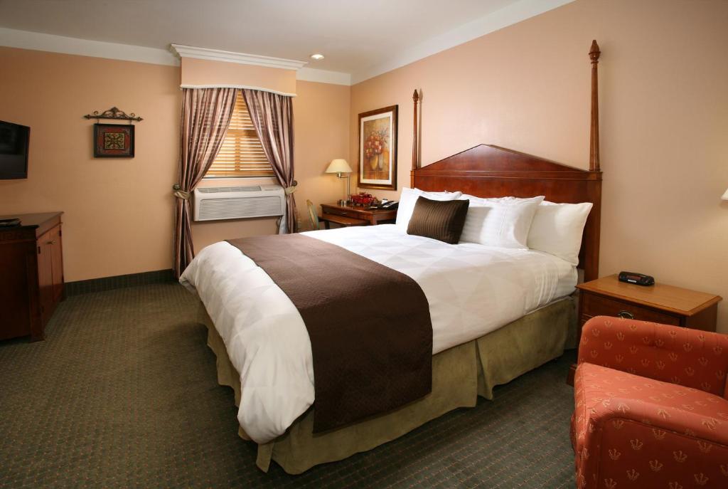 a hotel room with a large bed and a chair at Brand Plaza Hotel in Glendale