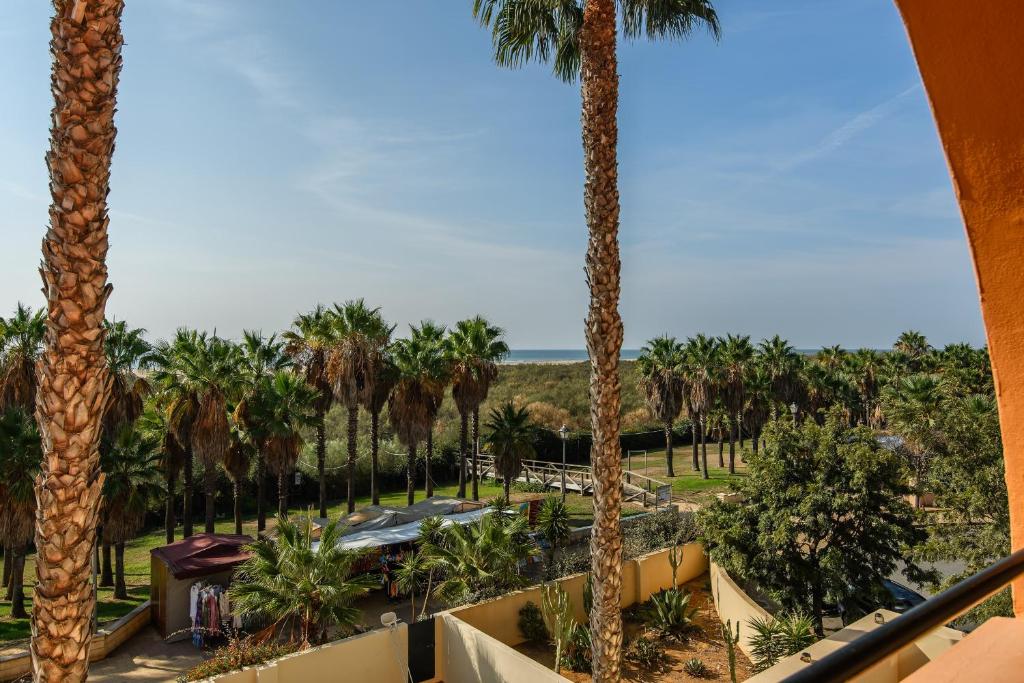 einen Blick auf Palmen vom Balkon eines Resorts in der Unterkunft Playa Marina by Ĥ - Playa Punta del Moral PPHM303P59 in Punta del moral