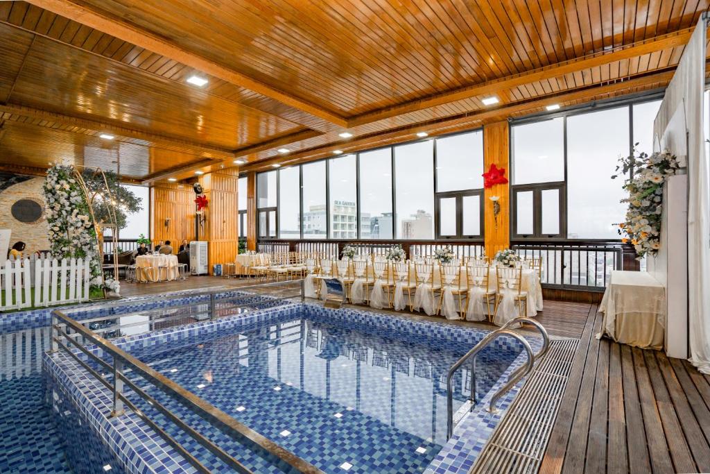 a pool with tables and chairs in a room with windows at Nhu Minh Plaza Danang Hotel in Danang