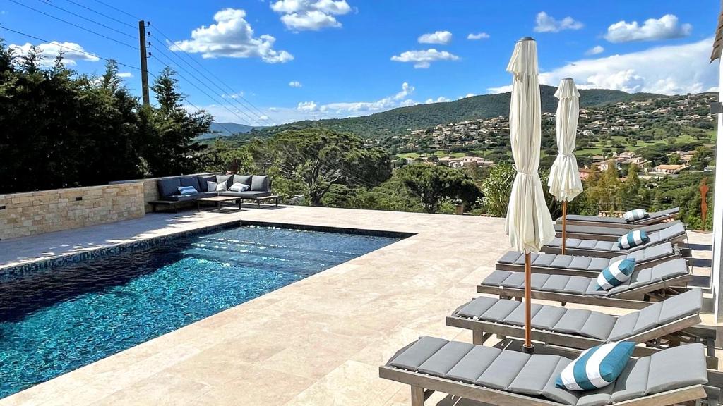 - une piscine avec des chaises longues et des parasols à côté de la piscine dans l'établissement Villa Les Geais, à Sainte-Maxime