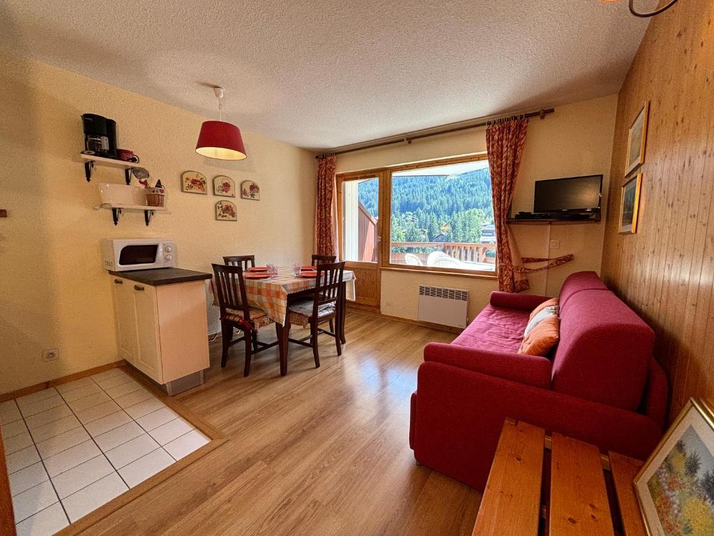 ein Wohnzimmer mit einem roten Sofa und einem Tisch in der Unterkunft Résidence Atrey 403 Clés Blanches Courchevel in Courchevel