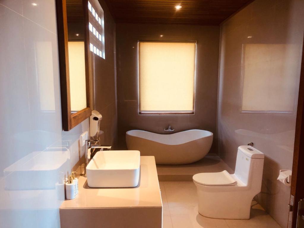 a bathroom with a tub and a toilet and a sink at Bali Natha Beach Front in Canggu