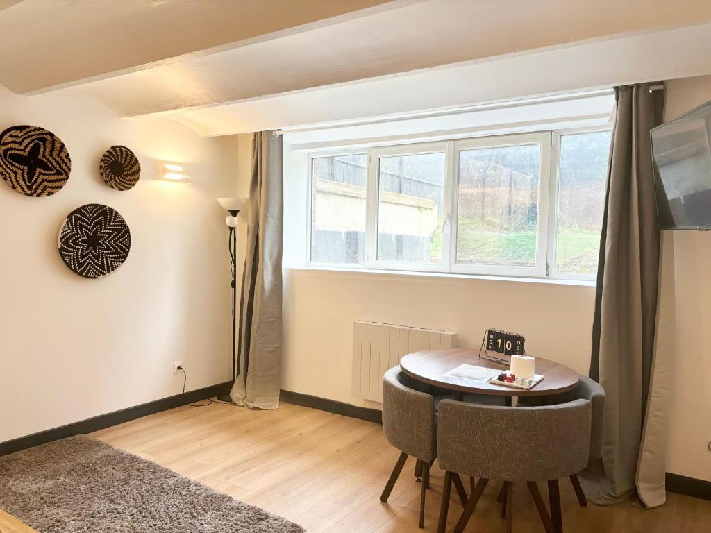 un salon avec une table et une fenêtre dans l'établissement Appartement confortable pour 4 voyageurs, à Roubaix