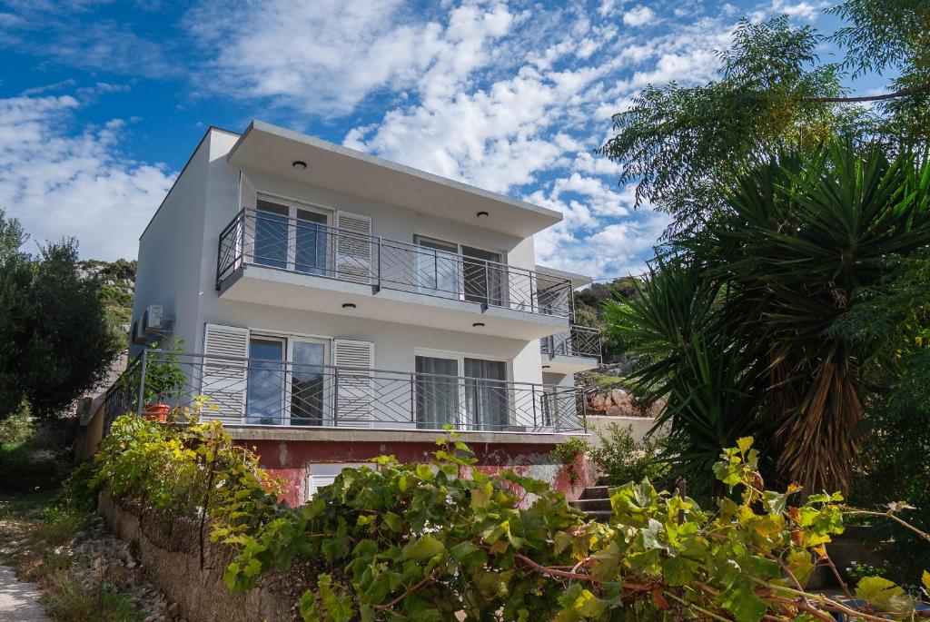 a white house with a balcony on a hill at Apartments Kate in Ražanj