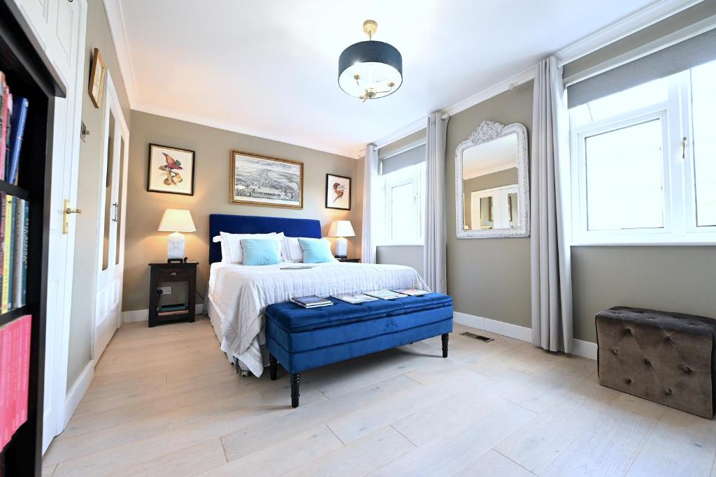 a bedroom with a blue bed and a blue ottoman at En-suite luxury large bedroom with parking and two tickets to Kew Gardens in Kew Gardens