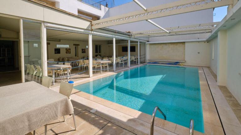 a large swimming pool in a building with a table at Camere a Sud in Alliste