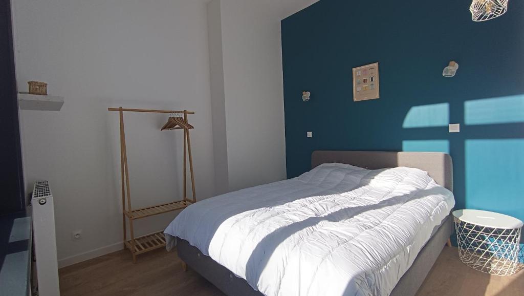 une chambre avec un lit avec un mur bleu dans l'établissement Le Calais Wilson 1, 4 pers, à Calais