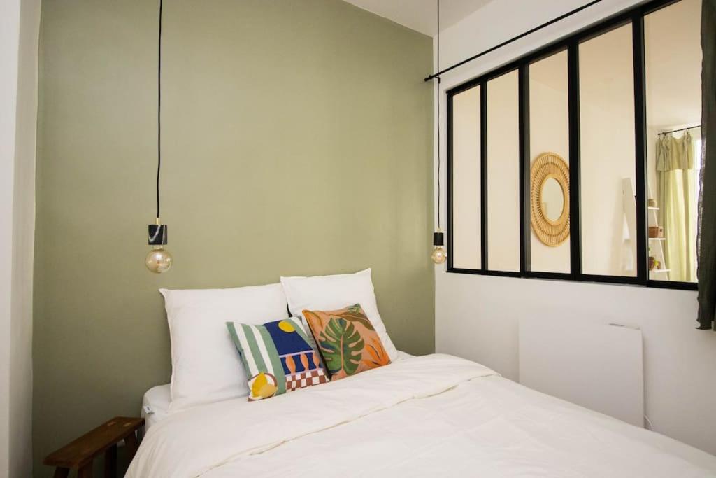 une chambre avec un lit blanc avec des oreillers et une fenêtre dans l'établissement CharmantT2 dans le quartier branché du Camas, à Marseille