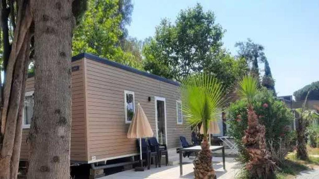 une petite cabine avec une table, des chaises et des arbres dans l'établissement Camping 4 étoiles - Parc aquatique - eece0c, à Grimaud