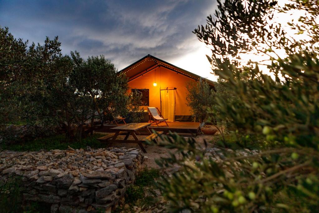 ein Haus mit einer Bank und einem Stuhl davor in der Unterkunft Adriatic Heritage Glamping No1 with Jacuzzi in Maslinica