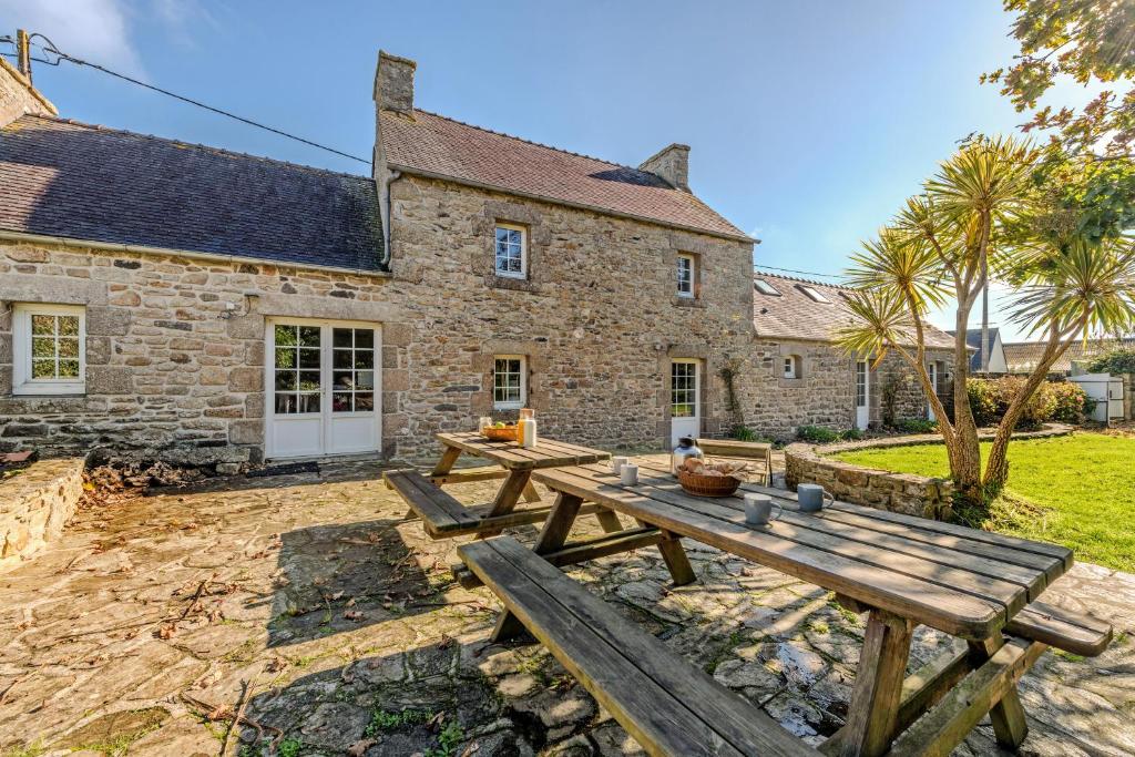 a wooden picnic table in front of a stone building at Ker Breizh - Saint Pabu - 14 pers in Saint-Pabu
