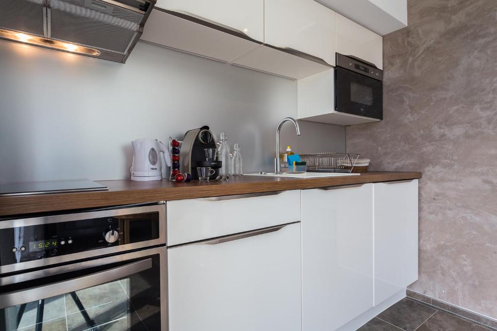 a kitchen with white cabinets and a sink at Villa Velvet in Villeneuve-Loubet