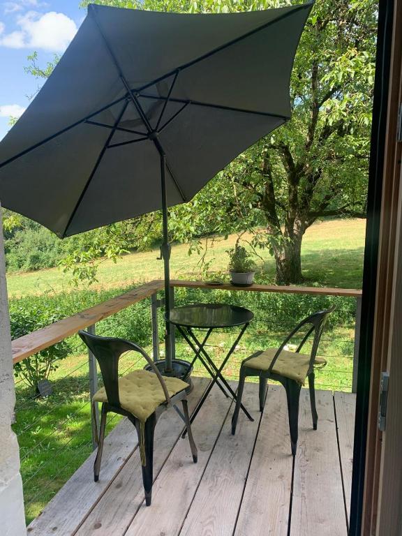 une table, deux chaises et un parasol sur une terrasse dans l'établissement Appartement moderne dans ferme rénovée, à Champagnole